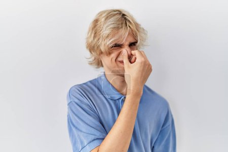 Photo for Young modern man standing over isolated background smelling something stinky and disgusting, intolerable smell, holding breath with fingers on nose. bad smell - Royalty Free Image