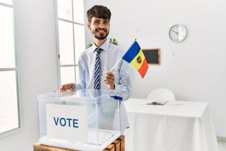 Foto de Joven votante hispano con bandera de Moldavia en colegio electoral. - Imagen libre de derechos