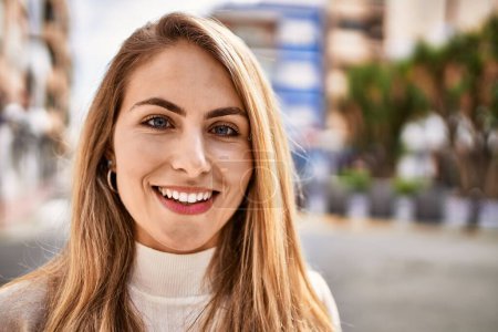 Téléchargez les photos : Jeune femme blonde souriant confiant à la rue - en image libre de droit