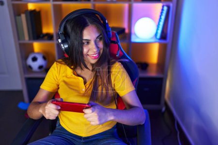 Photo for Young beautiful arab woman streamer playing video game using smartphone at gaming room - Royalty Free Image