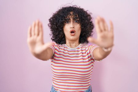 Foto de Joven mujer de Oriente Medio de pie sobre fondo rosa haciendo stop gesture con las manos palmas, enojado y expresión de frustración - Imagen libre de derechos