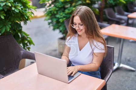 Photo for Young blonde woman using laptop sitting on table at coffee terrace - Royalty Free Image