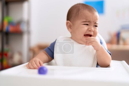 Foto de Adorable niño chino sentado en la silla de cena bebé llorando en casa - Imagen libre de derechos