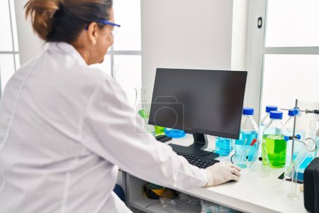 Photo for Middle age hispanic woman wearing scientist uniform using computer at laboratory - Royalty Free Image