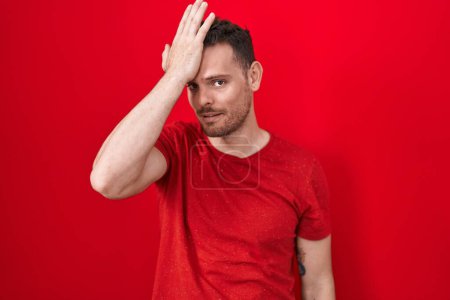 Photo for Young hispanic man standing over red background surprised with hand on head for mistake, remember error. forgot, bad memory concept. - Royalty Free Image