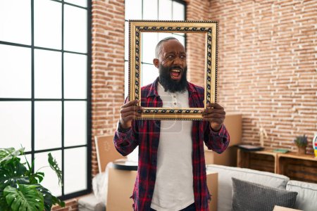 Photo for African american man putting face in empty frame angry and mad screaming frustrated and furious, shouting with anger. rage and aggressive concept. - Royalty Free Image