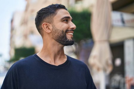 Foto de Hombre árabe joven sonriendo confiado mirando a un lado en la calle - Imagen libre de derechos