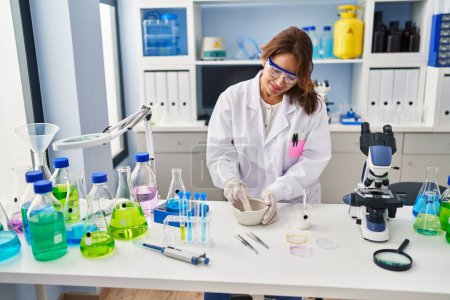 Téléchargez les photos : Jeune femme latine portant l'uniforme de scientifique travaillant au laboratoire - en image libre de droit