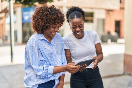 Photo for African american women mother and daughter watching video on touchpad at street - Royalty Free Image