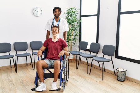 Téléchargez les photos : Deux hommes physiothérapeute et patient assis en fauteuil roulant ayant une consultation médicale dans la salle d'attente de l'hôpital - en image libre de droit