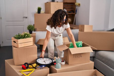 Téléchargez les photos : Middle age hispanic woman packing boxes at new home - en image libre de droit