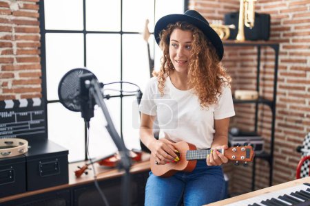 Téléchargez les photos : Jeune belle musicienne hispanique jouant de la guitare classique au studio de musique - en image libre de droit