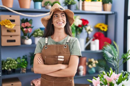 Foto de Joven hermosa florista hispana sonriendo confiada de pie con los brazos cruzados gesto en la tienda de flores - Imagen libre de derechos