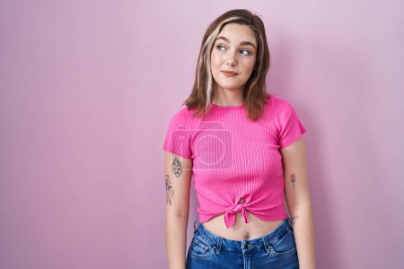 Photo for Blonde caucasian woman standing over pink background smiling looking to the side and staring away thinking. - Royalty Free Image