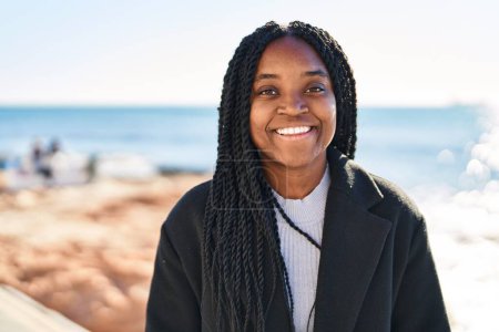 Foto de Mujer afroamericana sonriendo confiada de pie en la playa - Imagen libre de derechos