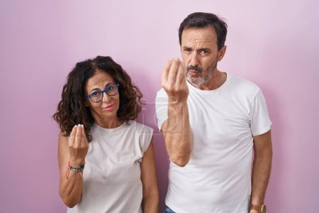 Téléchargez les photos : Couple hispanique moyen âge ensemble sur fond rose faisant geste italien avec expression confiante main et doigts - en image libre de droit