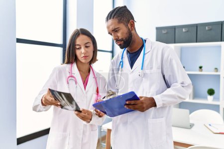 Photo for Man and woman wearing doctor uniform looking xray working at clinic - Royalty Free Image