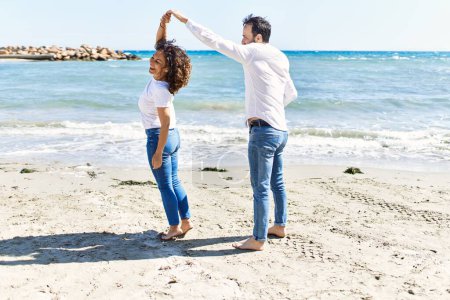 Photo for Middle age hispanic couple smiling happy dancing at the beach. - Royalty Free Image