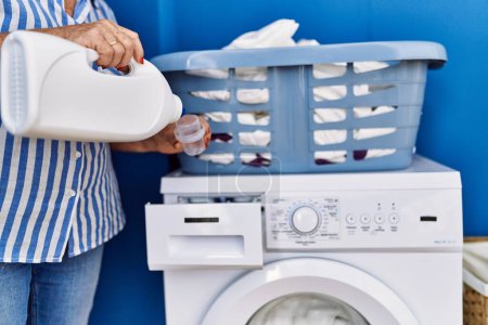 Photo for Senior grey-haired woman smiling confident pouring detergent on washing machine at laundry room - Royalty Free Image