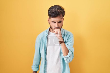 Photo for Young hispanic man with tattoos standing over yellow background feeling unwell and coughing as symptom for cold or bronchitis. health care concept. - Royalty Free Image