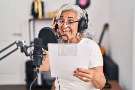 Téléchargez les photos : Femme musicienne d'âge moyen chantant au studio de musique - en image libre de droit