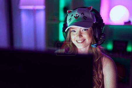 Foto de Transmisor de mujer joven usando computadora y auriculares en la sala de juegos - Imagen libre de derechos
