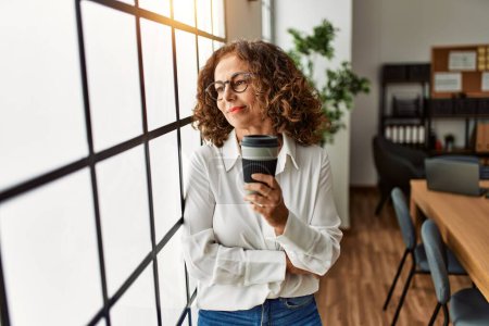 Téléchargez les photos : Mature hispanic woman working drinking a coffee at the office - en image libre de droit