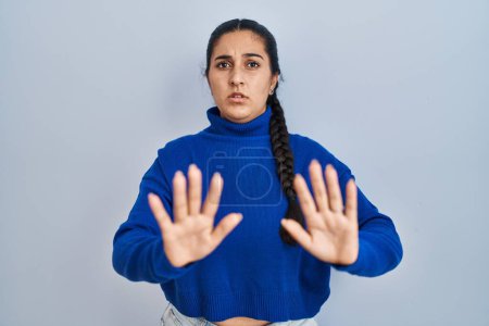 Photo for Young hispanic woman standing over isolated background moving away hands palms showing refusal and denial with afraid and disgusting expression. stop and forbidden. - Royalty Free Image