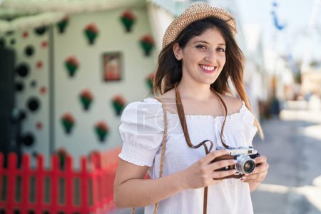 Téléchargez les photos : Young hispanic woman tourist smiling confident using camera at street - en image libre de droit