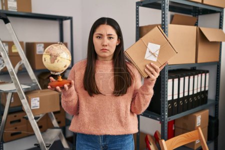 Photo for Young latin woman working at small business ecommerce doing world shipping skeptic and nervous, frowning upset because of problem. negative person. - Royalty Free Image