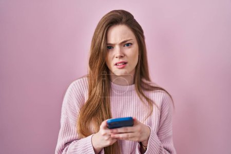 Photo for Young caucasian woman using smartphone typing message clueless and confused expression. doubt concept. - Royalty Free Image