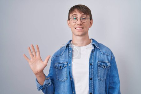 Téléchargez les photos : Caucasian blond man standing wearing glasses showing and pointing up with fingers number five while smiling confident and happy. - en image libre de droit