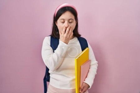 Photo for Woman with down syndrome wearing student backpack and holding books bored yawning tired covering mouth with hand. restless and sleepiness. - Royalty Free Image