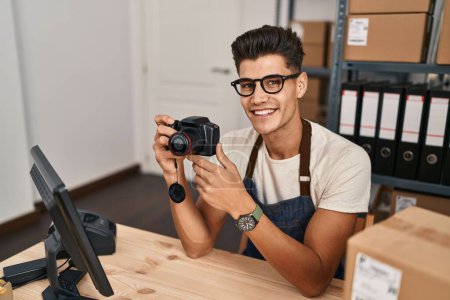 Photo for Young hispanic man ecommerce business worker using professional camera at office - Royalty Free Image