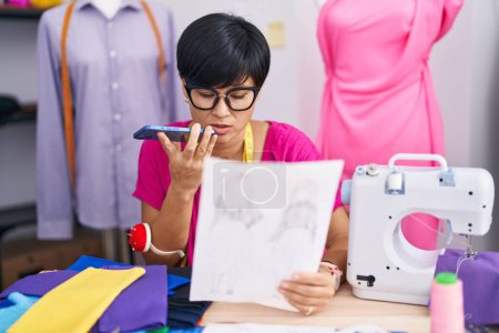 Téléchargez les photos : Femme chinoise du Moyen Age parlant sur smartphone regardant la conception de vêtements à l'atelier - en image libre de droit
