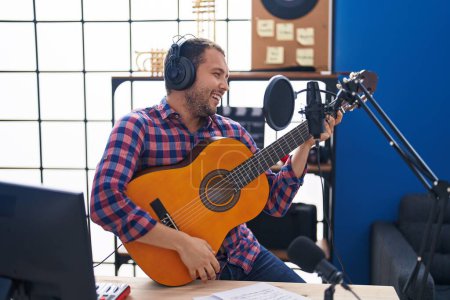 Téléchargez les photos : Young man musician singing song playing classical guitar at music studio - en image libre de droit