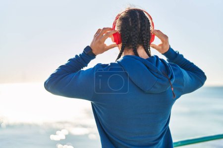 Téléchargez les photos : Young man listening to music on back view at seaside - en image libre de droit