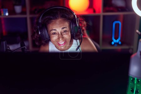 Photo for Middle age woman streamer playing video game using computer at gaming room - Royalty Free Image