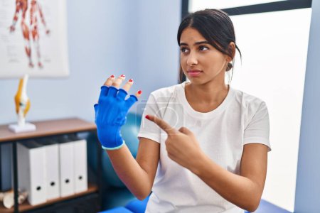 Photo for Young latin woman patient wearing bandage suffering for hand injury at physiotherapy clinic - Royalty Free Image