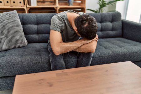 Téléchargez les photos : Young hispanic man psychology patient depressed sitting on sofa at clinic - en image libre de droit