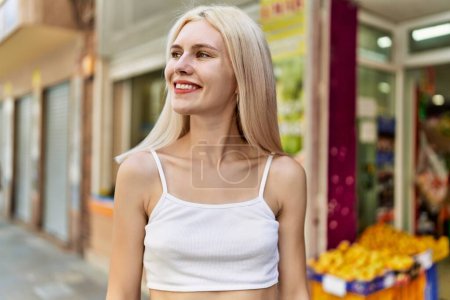 Téléchargez les photos : Jeune fille blonde souriant heureux debout à la ville. - en image libre de droit