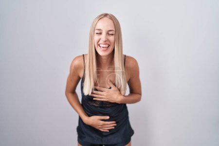 Foto de Young caucasian woman wearing nightgown smiling and laughing hard out loud because funny crazy joke with hands on body. - Imagen libre de derechos