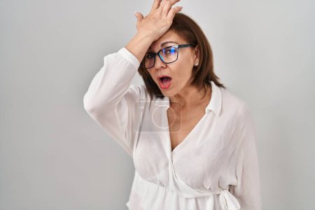 Photo for Middle age hispanic woman standing over isolated background surprised with hand on head for mistake, remember error. forgot, bad memory concept. - Royalty Free Image