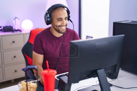 Foto de Joven streamer latino jugando videojuegos usando computadora en la sala de juegos - Imagen libre de derechos