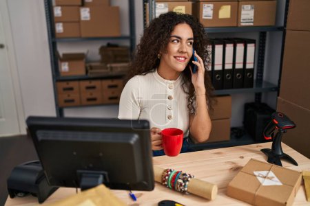 Téléchargez les photos : Jeune belle hispanique femme commerce électronique travailleur d'affaires parler sur smartphone boire du café au bureau - en image libre de droit