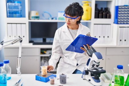 Téléchargez les photos : Jeune femme scientifique mesurant le liquide au laboratoire - en image libre de droit