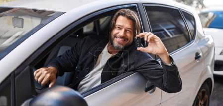 Foto de Hombre de mediana edad sonriendo confiado sosteniendo la llave del coche nuevo en la calle - Imagen libre de derechos