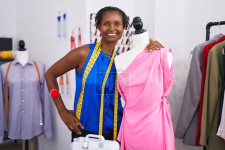 Téléchargez les photos : Middle age african american woman tailor smiling confident leaning on manikin at atelier - en image libre de droit