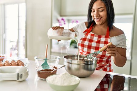 Photo for Hispanic brunette woman preparing chocolate cake at the kitchen - Royalty Free Image