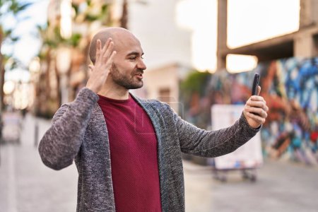 Téléchargez les photos : Jeune homme souriant confiant ayant appel vidéo à la rue - en image libre de droit